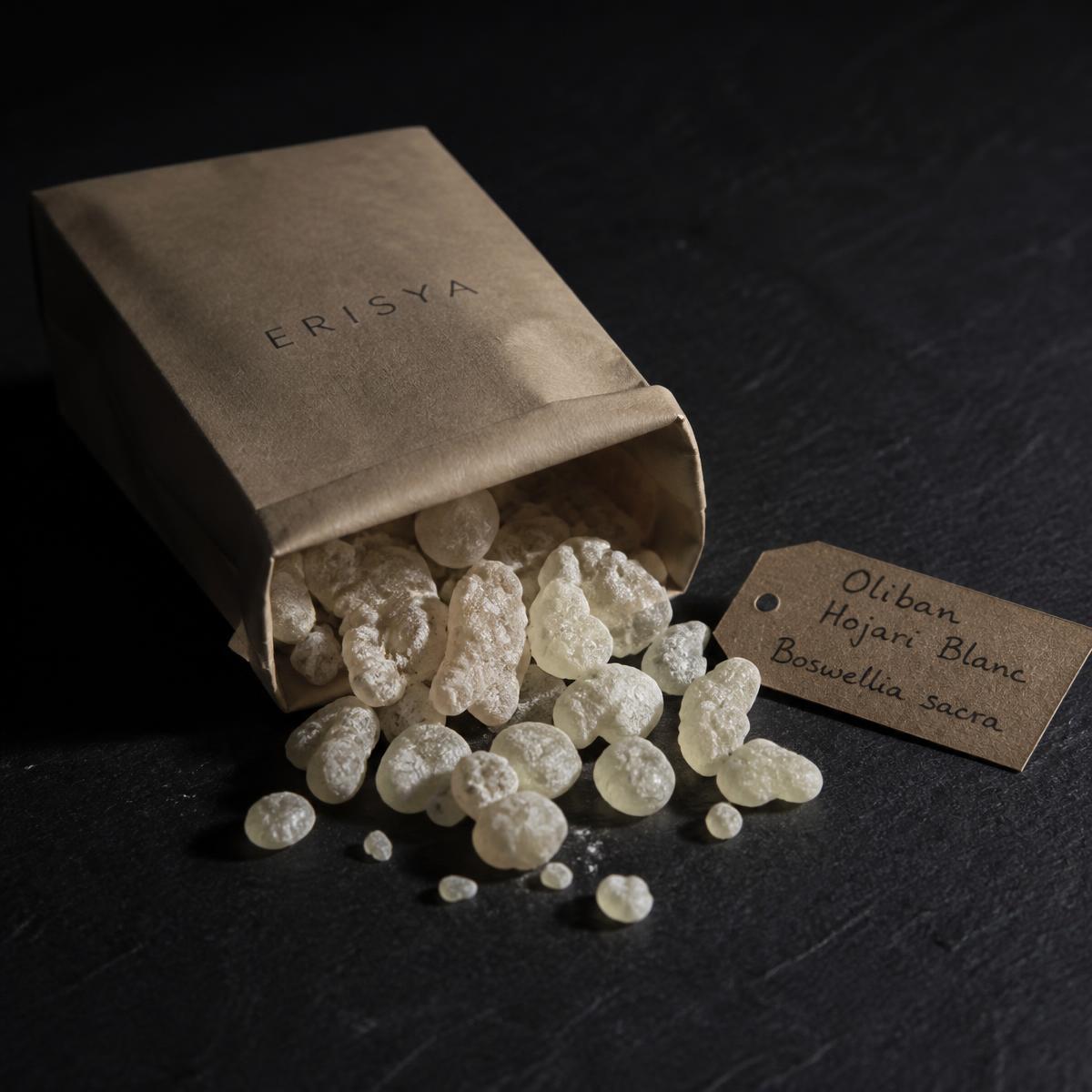 Larmes d'oliban Hojari blanc de Boswellia sacra posées sur une ardoise sombre, éclairage rasant.